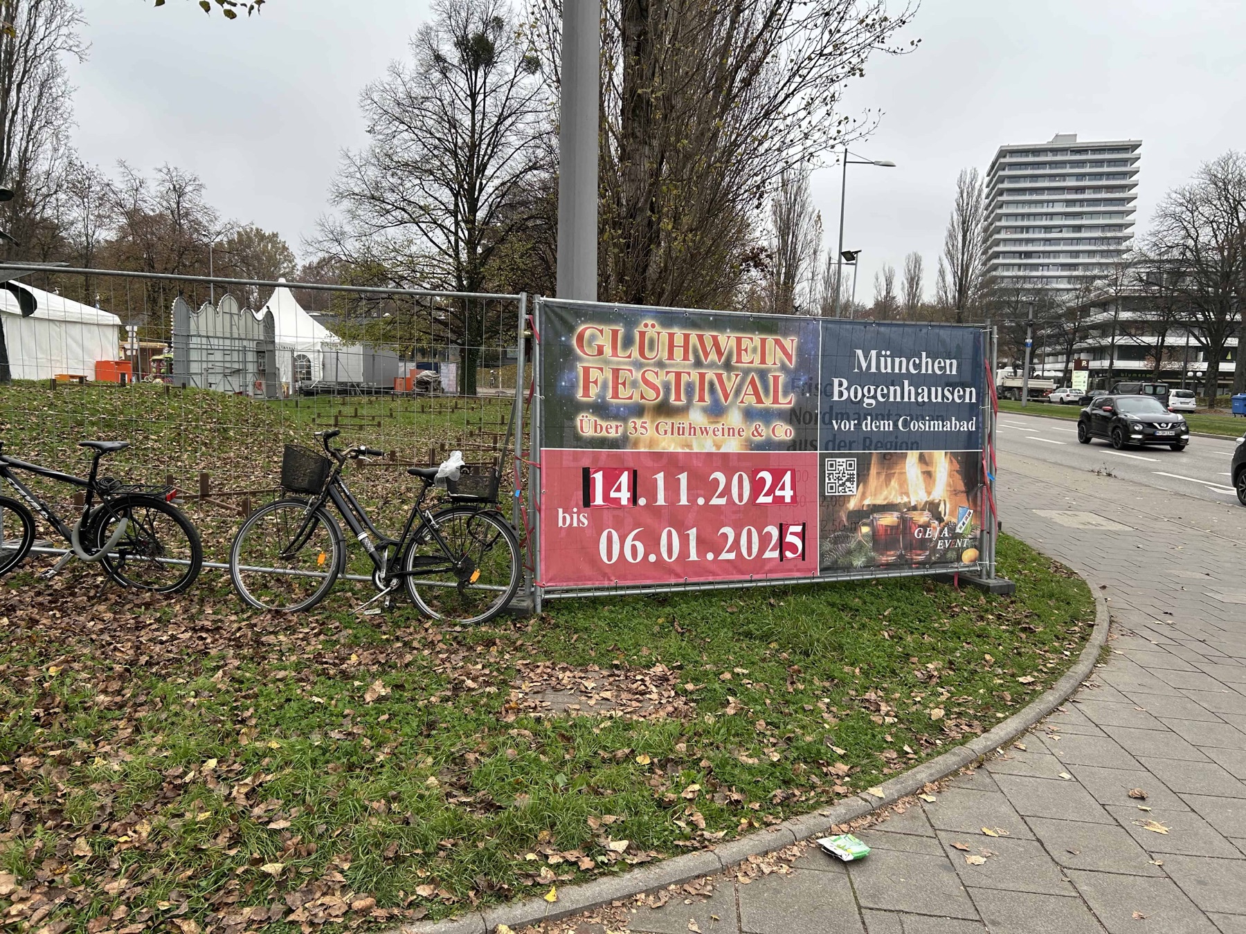 Banner am Bauzaun: „Glühwein Festival“ in München-Bogenhausen vor dem Cosimabad, daneben abgestellte Fahrräder