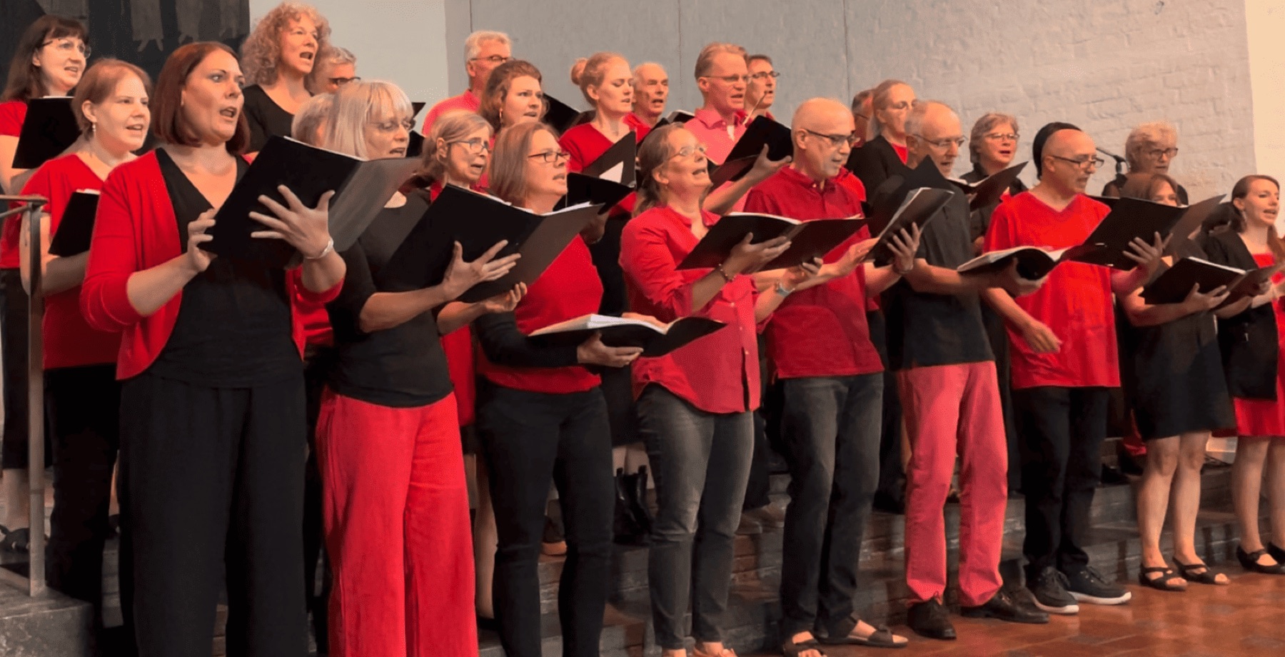 Die Munich Souls in Rot und Schwarz singen aus ihren Notenmappen beim Konzert 2023