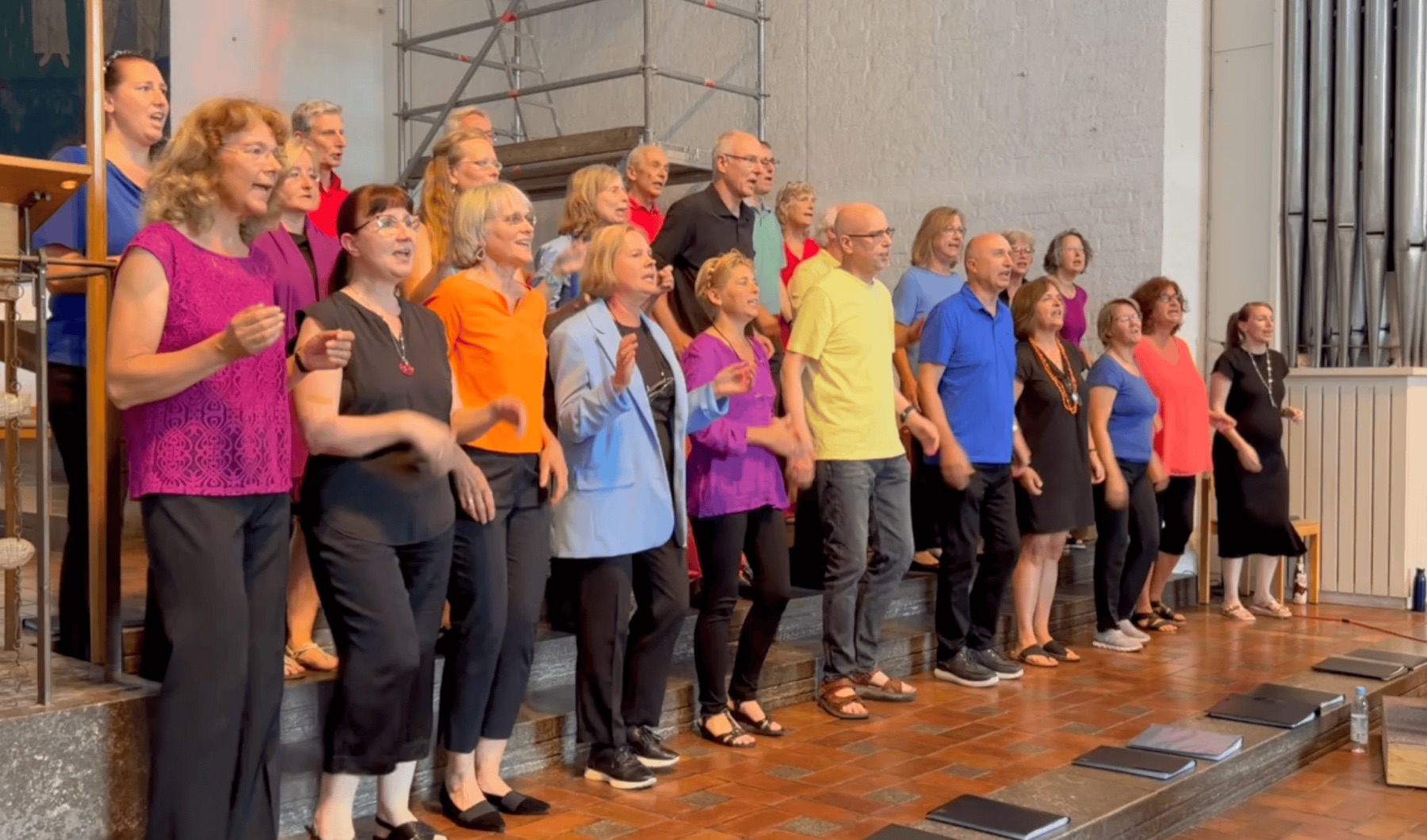 Die Munich Souls singen beim Sommerkonzert 2024 in bunten Oberteilen vor der Orgel von St. Klara